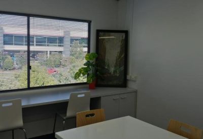 Co-working space with a window-side counter, stools, and a view of neighboring buildings.
