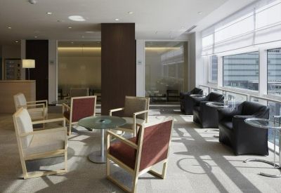 Sunlit communal lounge with comfortable armchairs and floor-to-ceiling windows.