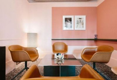 Small meeting area with leather armchairs and pink feature walls.