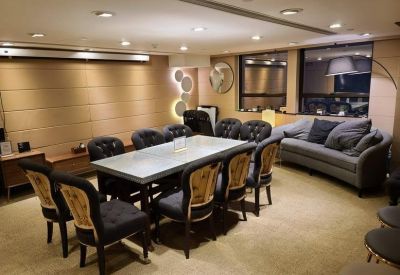 A sophisticated meeting room with a long table, tufted black chairs, and a grey sofa.