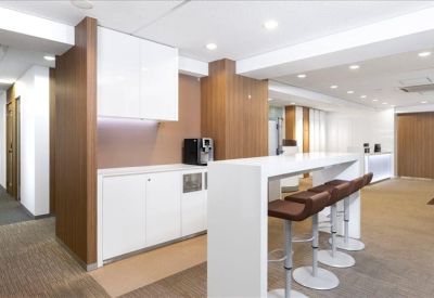 Communal break area with a white kitchen island, bar stools, and coffee machine.