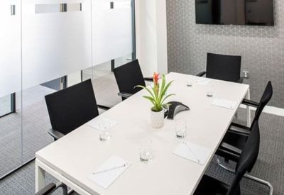 Professional meeting room with a white table, black chairs, and a potted plant.