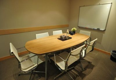 Small professional meeting room with a wooden oval table and whiteboard.