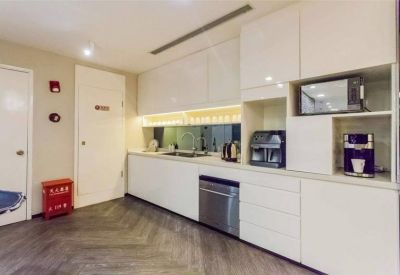 Modern kitchen and breakout area with white cabinetry, a microwave, and a coffee machine.