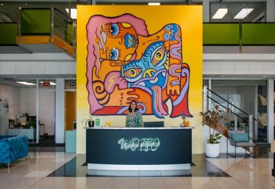 Wide view of the reception area showcasing the full-scale vibrant mural and front desk.
