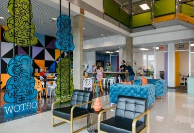 Vibrant communal lounge with blue tufted sofas and colourful Maori-inspired art panels.