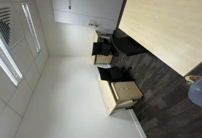 Small internal office featuring two desks and overhead panel lighting.