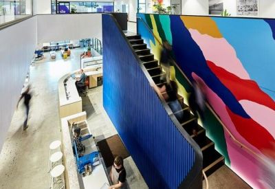 Bright multi-level office lobby with a vibrant colorful mural beside a central staircase.