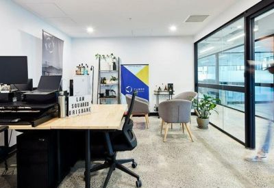 Private office space with an adjustable standing desk, dual monitors, and guest seating.