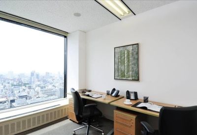 Bright corner office with two workstations and a large window overlooking the city skyline.