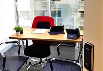 Private office suite with a wooden desk, red accent chair, and large window.