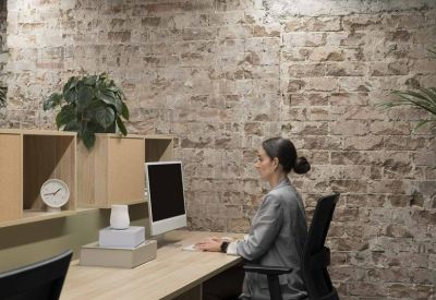 Bright workspace featuring a long wooden desk and a rustic exposed brick wall.