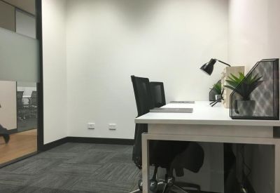Bright internal private office with two desks and desktop plants.