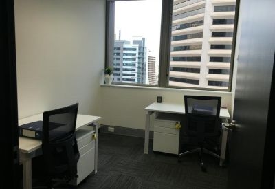 Corner office with two desks and large windows offering city views.