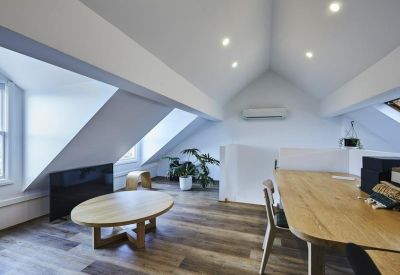 Spacious top floor workspace with vaulted ceilings and wooden oval table.