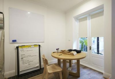 Meeting room featuring a round timber table, whiteboard, and French doors.
