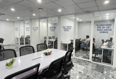 Modern workspace area with white desks, glass walls, and motivational typography.