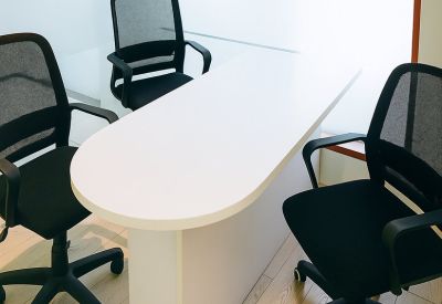 Private internal office with a white oval table and ergonomic black mesh chairs.