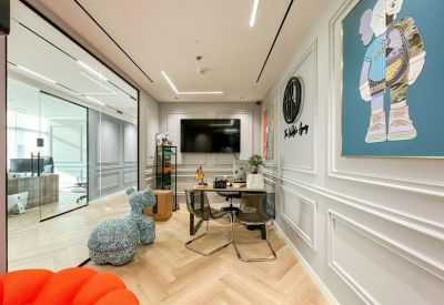 Small private office with a meeting table, wall art, and light wood floors.