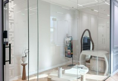Transparent glass-walled meeting room with minimalist white furniture.