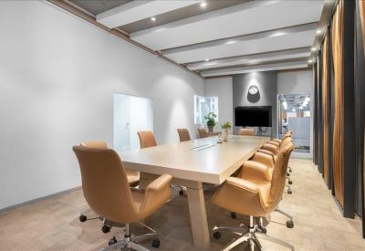Bright boardroom featuring a long wooden table, tan leather chairs, and contemporary ceiling panels.