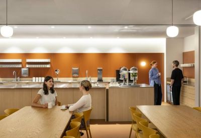 Bright communal kitchen and dining area featuring a terracotta feature wall and light wood cabinetry.