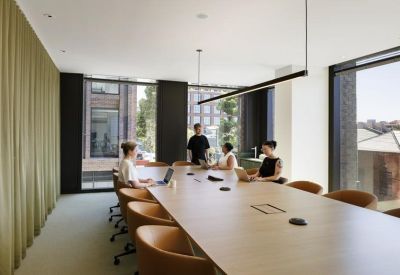 Modern meeting room with a long timber table, leather chairs, and olive green curtains.