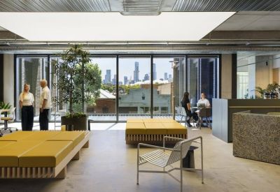 Sunlit breakout space with yellow daybeds and large windows offering views of the city skyline.