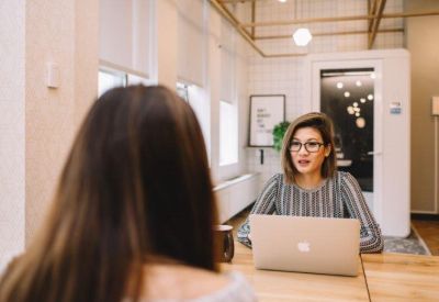 Professional interview setting with a woman at a laptop in a bright office.