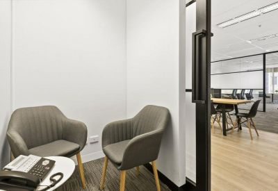 Small meeting room with two grey armchairs and a side table.