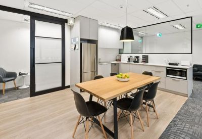 Modern breakout kitchen with a wooden dining table and black chairs.