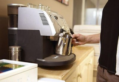Man using a professional espresso machine in a modern breakout area.