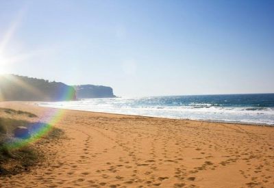 Sun-drenched beach with golden sand and blue waves crashing on the shore.