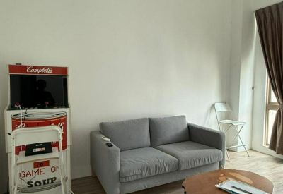 Relaxation area with a grey couch and arcade game.