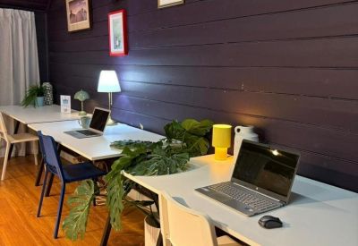 Workstation setup with a laptop, lamp, and green plants against a wood-paneled wall.