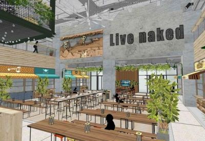Bright communal dining area with wooden tables, indoor plants, and Live naked signage.