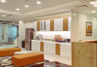 Modern office kitchen with white cabinetry and wooden accents.