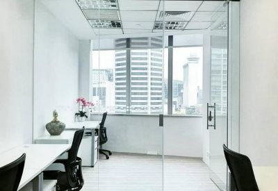 Shared office space featuring white desks and a glass partition.