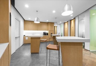 Sleek communal kitchen area with high tables, wooden cabinetry, and pendant lighting.
