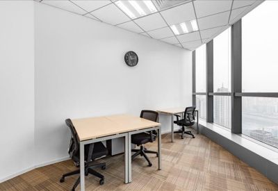 Bright corner office with two desks and expansive city views through floor-to-ceiling windows.