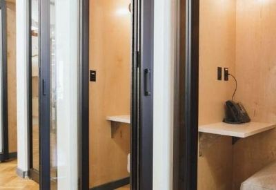 Private glass-fronted phone booths with light wood interiors and built-in desks.