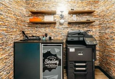 Utility area with a printer and shredding bin against a textured stacked-stone feature wall.