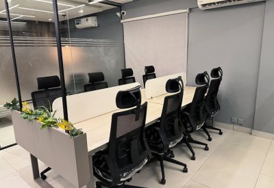 Compact workspace with eight office chairs and dividers.