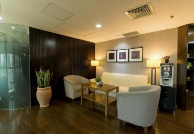 Cozy lounge area with grey armchairs, a wooden coffee table, and framed art.