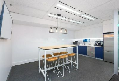 Modern communal kitchen with a high breakfast table, blue cabinetry, and stainless steel appliances.
