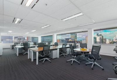 Open-plan office area with multiple workstations and large windows overlooking the city.