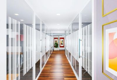 Long office corridor with glass partitions and warm wooden flooring.