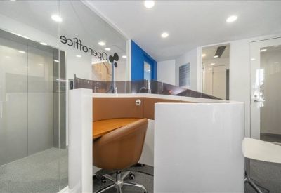 Modern reception area with a curved white and wood desk under bright recessed lighting.
