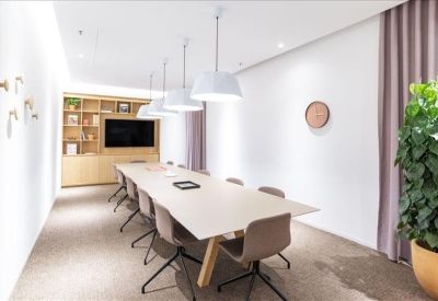 Minimalist meeting room with a long white table, neutral-toned chairs, and light wood cabinetry.