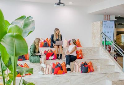 Communal tiered seating area with colorful pillows and indoor plants.